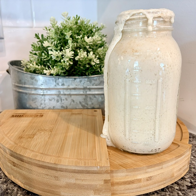 Active sourdough starter (levain) with bubbles in a glass jar, top view